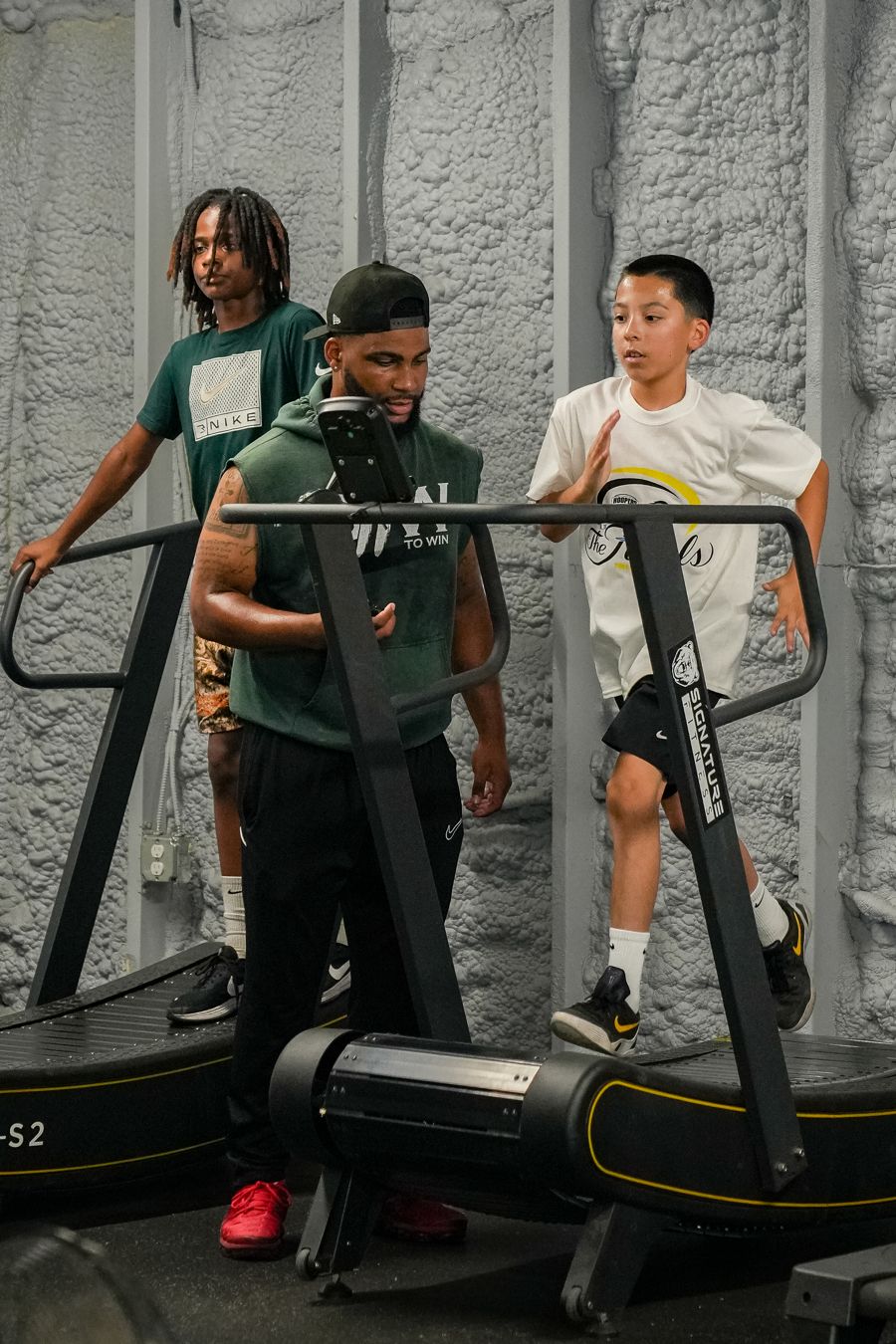 Coach timing youth athletes sprinting on curved treadmills