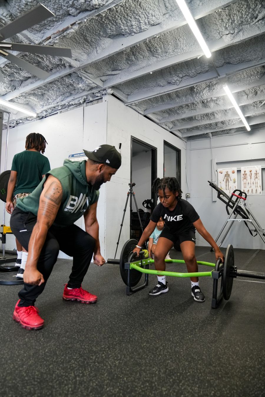 Coach demonstrating a trap bar lift to a young athlete